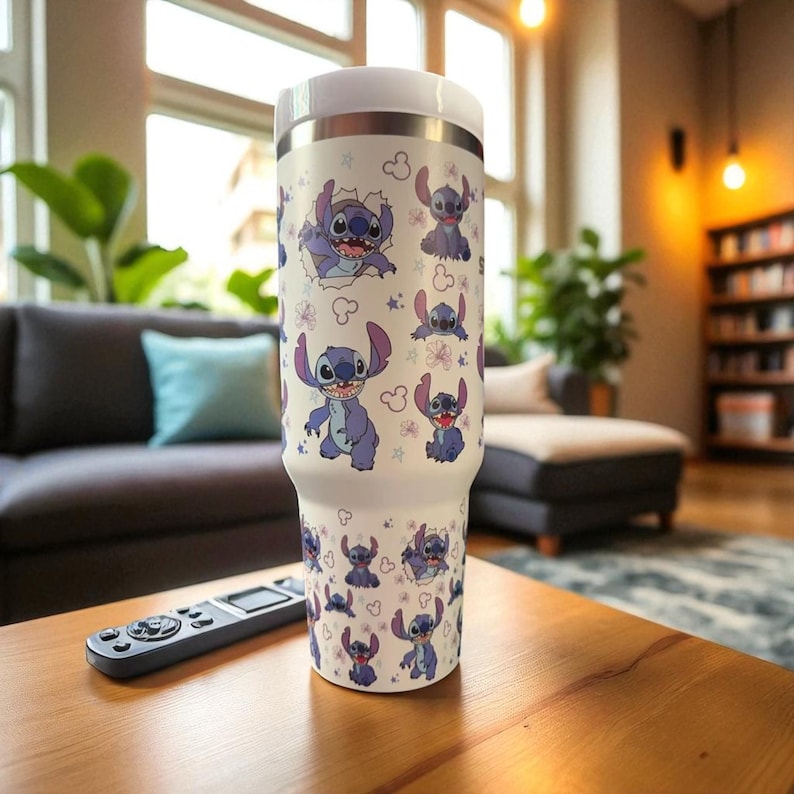 May include: A white insulated tumbler featuring a repeating pattern of the character Stitch from the Disney movie Lilo & Stitch. The tumbler has a white lid and a silver rim. The design includes Stitch in various poses with purple flowers and clouds.