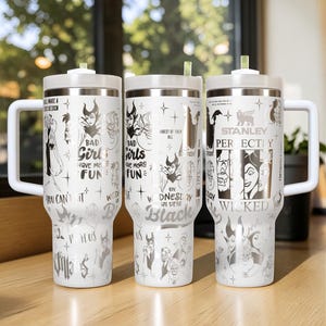 Puede incluir: Tres vasos aislados blancos con tapas y asas plateadas. Cada vaso presenta un dise&ntilde;o diferente con ilustraciones en negro y plata de personajes villanos y texto que dice "Bad Girls Have More Fun" y "On Wednesday We Wear Black".