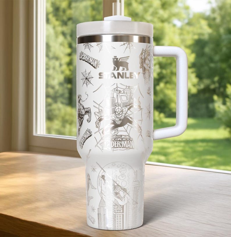 Pu&ograve; includere: Bicchiere Stanley bianco con grafica di Spider-Man. Il bicchiere ha un manico, un coperchio e una cannuccia bianchi. Il design include Spider-Man, ragnatele e paesaggi urbani. Il logo Stanley &egrave; visibile. Questo bicchiere isolato &egrave; progettato per mantenere le bevande fredde o calde.