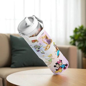 May include: A white and grey water bottle with a handle, decorated with cartoon characters. The bottle is on a wooden table in a room. The characters include Mickey and Minnie Mouse, Buzz Lightyear, and others. The bottle is likely to hold around 750ml.