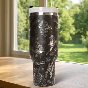 Pu&ograve; includere: Bicchiere nero con coperchio e cannuccia bianchi, con un motivo ripetuto di illustrazioni di Spider-Man e ragnatele. Il bicchiere ha la scritta "SPIDERMAN" in argento. Il bicchiere &egrave; su una superficie di legno.