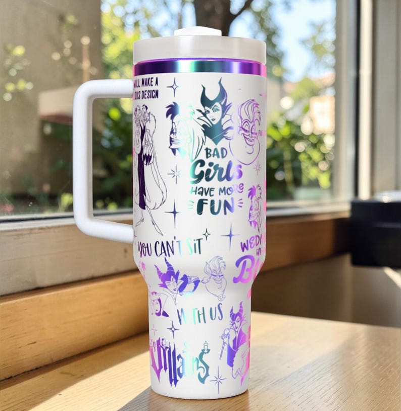 Puede incluir: Vaso t&eacute;rmico blanco con asa, con ilustraciones de villanos de Disney y el texto "BAD Girls HAVE MORE FUN". El vaso tiene una tapa blanca y una banda morada y plateada en la parte superior.