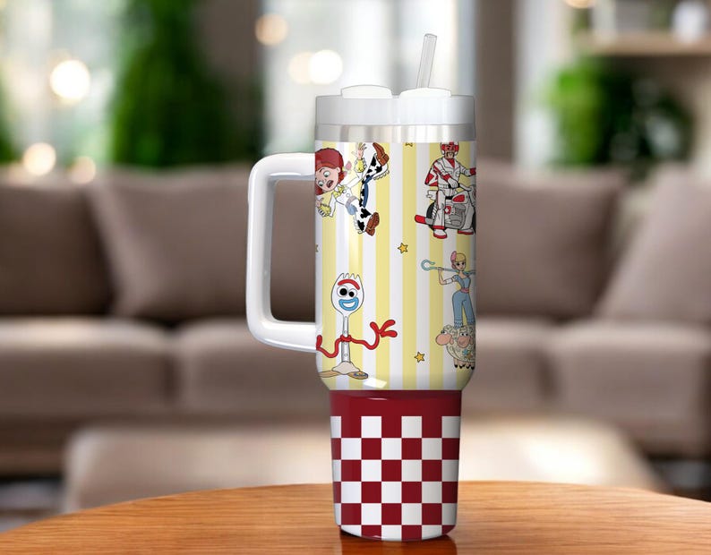 May include: A white and red tumbler with a handle and straw. The tumbler features cartoon characters on a yellow and white striped background. The bottom of the tumbler has a red and white checkered pattern.