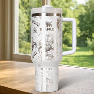 Pu&ograve; includere: Bicchiere Stanley bianco con grafica di Spider-Man e la scritta "YOUR NAME". Il bicchiere ha un manico e un coperchio bianchi, con un design argentato di Spider-Man, ragnatele e il logo Stanley. Capacit&agrave; di circa 1,18 litri.
