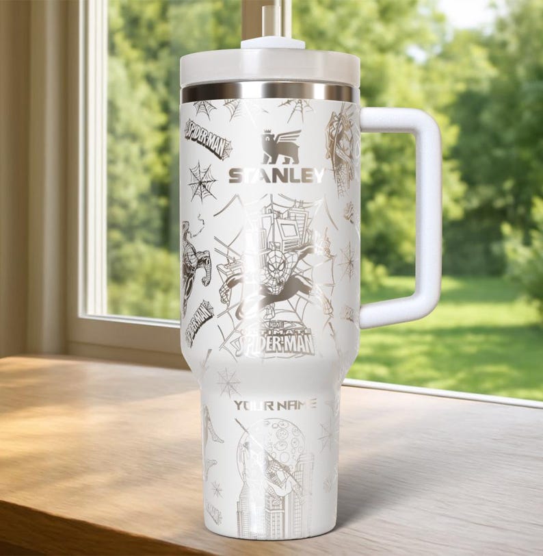Pu&ograve; includere: Bicchiere Stanley bianco con grafica di Spider-Man e la scritta "YOUR NAME". Il bicchiere ha un manico e un coperchio bianchi, con un design argentato di Spider-Man, ragnatele e il logo Stanley. Capacit&agrave; di circa 1,18 litri.