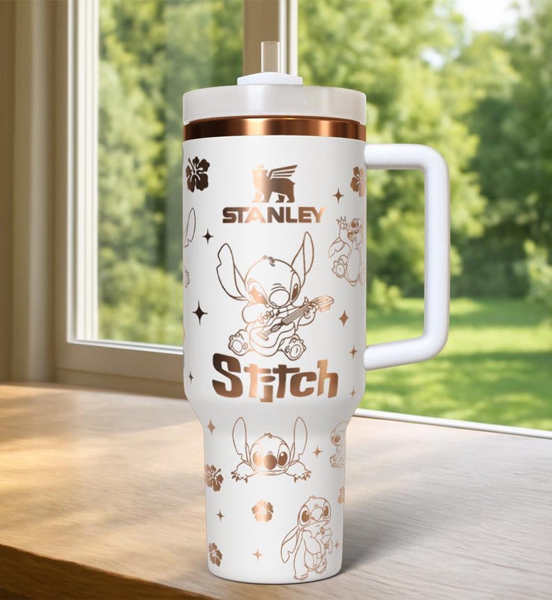May include: White Stanley tumbler with a handle, featuring a rose gold band and Stitch character graphics. The tumbler includes the Stanley logo and the word "Stitch". The design includes floral and star accents.