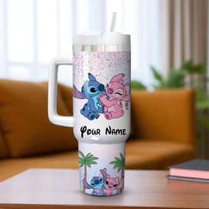 May include: A white insulated tumbler with a handle and a straw. The tumbler features a cartoon illustration of Stitch and Angel, with the text "Your Name" and a palm tree design. The background has pink confetti.