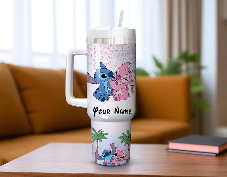 May include: A white insulated tumbler with a handle and a straw. The tumbler features a cartoon illustration of Stitch and Angel, with the text "Your Name" and a palm tree design. The background has pink confetti.