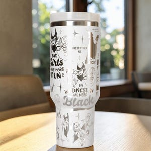 Puede incluir: Vaso t&eacute;rmico blanco con tapa y detalles plateados. El vaso presenta ilustraciones de villanos de Disney y las frases "Bad Girls Have More Fun" y "On Wednesday We Wear Black."
