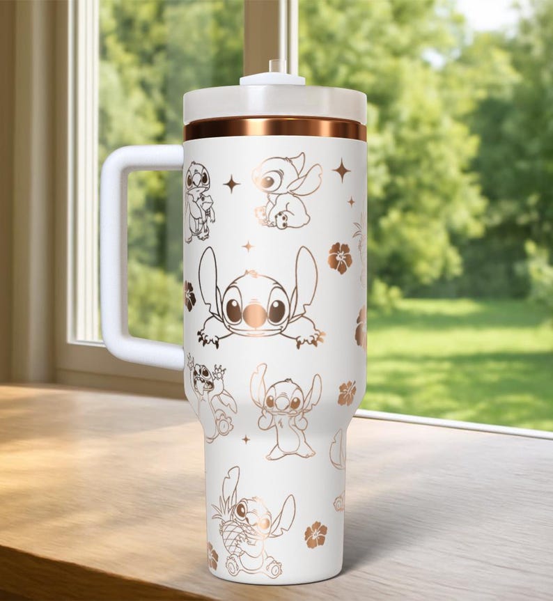 May include: White tumbler with a handle, featuring a copper-colored band and lid. The tumbler is adorned with copper-colored illustrations of the character Stitch from Lilo & Stitch, along with floral and star accents. The tumbler has a white handle.