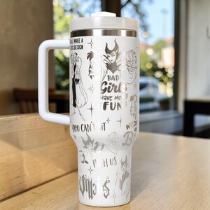 Puede incluir: Vaso t&eacute;rmico blanco con asa, con ilustraciones de villanos de Disney y el texto "BAD Girls HAVE MORE FUN". El vaso tiene tapa y asa blancas, para bebidas fr&iacute;as o calientes.