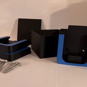 Könnte beinhalten: Ein Satz schwarzer und blauer Wandhalterungen mit Schrauben. Die Halterungen sind für die Montage eines Regals oder eines anderen Objekts konzipiert.