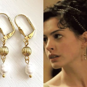 May include: Gold earrings with a pearl and a textured gold bead. The earrings have a clip-on closure.