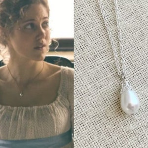 May include: A silver chain necklace with a large, pear-shaped white pearl pendant.