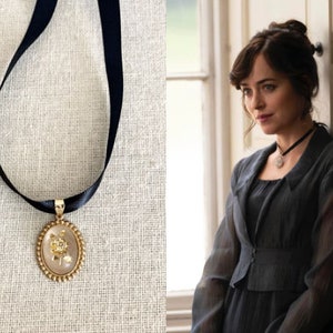 May include: A black ribbon choker necklace with a gold oval pendant featuring a rose design.