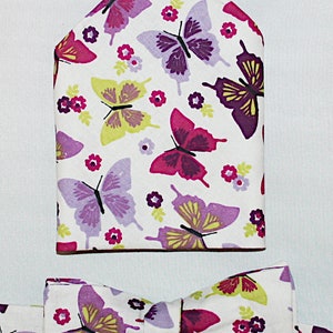 May include: A white pocket square and bow tie with a butterfly pattern in shades of purple, pink, and yellow. The fabric has a white background with small white flowers.