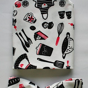 Pode incluir: Uma gravata borboleta branca com um padrão de cozinha preto e vermelho. O padrão inclui imagens de utensílios de cozinha, comida e as palavras "Sal" e "Pimenta".