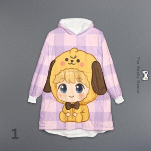 May include: A hooded blanket featuring a cartoon character in a yellow dog costume with brown ears and a bow tie. The blanket has a pink and purple plaid pattern and white lining. The text "The Geeky Gamer" is visible.