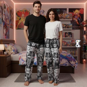 Op de afbeelding: Een stel staat naast elkaar, beiden gekleed in een pyjamabroek met een zwart-wit gezichtenpatroon. De persoon links draagt een zwart t-shirt, de persoon rechts een wit t-shirt. Anime posters zijn zichtbaar op de achtergrond.