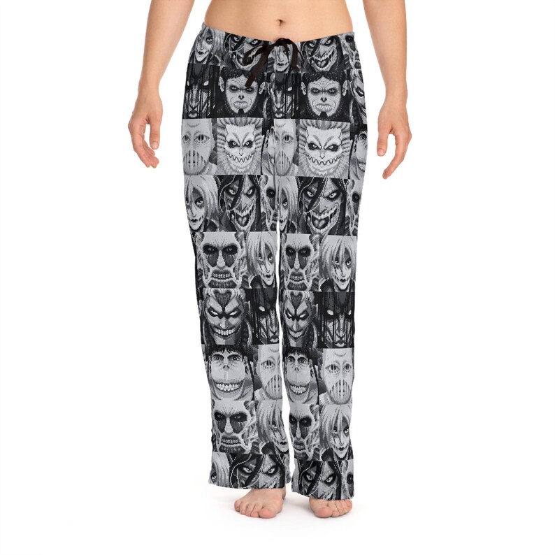 Op de afbeelding: Zwart-witte pyjamabroek met een herhalend patroon van gestileerde gezichten. De broek heeft een taille met trekkoord en een relaxte pasvorm. De gezichten hebben verschillende uitdrukkingen en ontwerpen, wat een unieke en opvallende look cre&euml;ert.