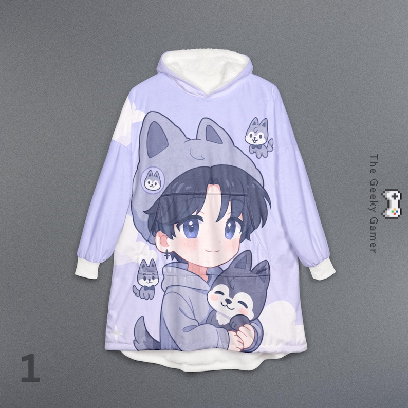 May include: A light purple hooded blanket featuring a cartoon illustration of a boy with blue eyes and a wolf hat, holding a wolf. The blanket has white cuffs and a white-lined hood. The text "The Geeky Gamer" is on the right side.