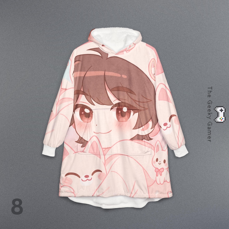 May include: A pink hooded blanket featuring a large anime-style character with brown hair and large pink eyes. The blanket is covered in a repeating pattern of cartoon bunnies and the character's face. The Geeky Gamer logo is visible.