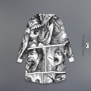 May include: Black and white hooded blanket featuring a manga-style illustration of screaming faces and monstrous figures. The blanket has white cuffs and a hood, with the text "The Geeky Gamer" on the side.