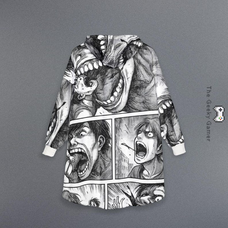 May include: Black and white hooded blanket featuring a manga-style illustration of screaming faces and monstrous figures. The blanket has white cuffs and a hood, with the text "The Geeky Gamer" on the side.