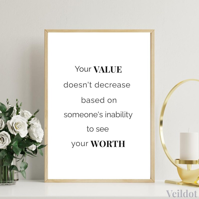 Minimalist wall art: ‘Your value doesn’t decrease because someone can’t see your worth’ in gold frame on neutral shelf