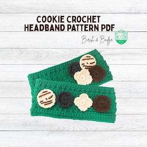Könnte beinhalten: Zwei grüne gehäkelte Stirnbänder mit braunen, weißen und beigefarbenen gehäkelten Keksdesigns. Die Stirnbänder befinden sich auf einem weißen Holzgrund. Der Text "Cookie Crochet Headband Pattern PDF" und "Birch & Badge" befindet sich oben im Bild.