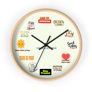 Puede incluir: Un reloj de pared redondo con marco de madera clara y esfera color crema. El reloj presenta manecillas negras y varias frases y gráficos motivacionales, incluyendo "Time to Breathe" y "Good Vibes Only."