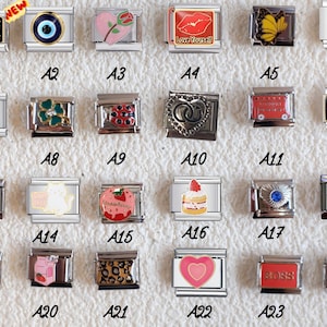 May include: A collection of twenty-four rectangular stainless steel modular bracelet links featuring various enamel and metal designs, including hearts, animals, food items, symbols, and text such as Bitch, Love Yourself, and Shit Happens.