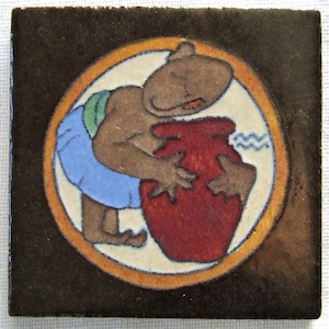 Puede incluir: Azulejo cerámico cuadrado con una figura de dibujos animados en marrón, azul y verde, sosteniendo un jarrón rojo. La figura está dentro de un círculo blanco con un borde naranja, sobre un fondo marrón oscuro. El azulejo tiene un acabado brillante.