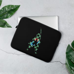 Peut inclure: Housse d'ordinateur portable noire avec une silhouette colorée d'un personnage d'anime avec une épée. Le design comprend des accents verts, rouges, bleus et jaunes. La housse a une fermeture éclair noire et est conçue pour un ordinateur portable.