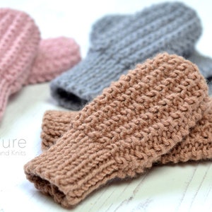 May include: Three pairs of knitted fingerless gloves in pink, gray, and brown. The gloves are made with a textured stitch pattern. The text "Pure Hand Knits" is visible in the image.