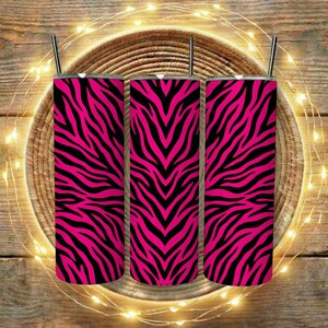 Puede incluir: Tres vasos de acero inoxidable con pajitas negras, cada uno con un llamativo diseño de rayas de cebra rosas y negras. Los vasos cilíndricos parecen aislados, adecuados para bebidas frías o calientes. El diseño es llamativo y audaz.