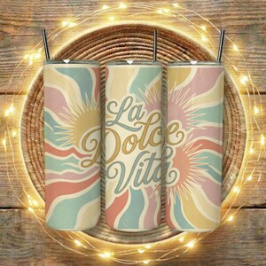 Puede incluir: Tres vasos aislados con un diseño retro que presenta un sol y líneas onduladas en colores pastel. El texto "La Dolce Vita" se muestra en el vaso central. Cada vaso tiene una pajita plateada.