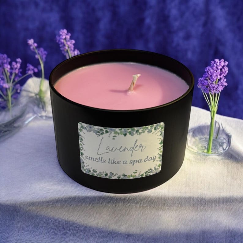 May include: A black candle jar with a pink wax candle inside. The jar has a label that reads "Lavender smells like a spa day".