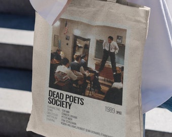 Könnte beinhalten: Beige Tragetasche mit einem Filmplakat für "Dead Poets Society". Das Poster zeigt eine Klassenzene mit dem Filmtitel, den Credits und dem Jahr 1989. Die Tasche wird von einer Person getragen, die ein weißes Hemd und blaue Jeans trägt.