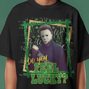 May include: Black t-shirt with a green and gold graphic of a horror movie character holding a knife. The graphic says "Do you feel lucky?"