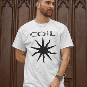 May include: White t-shirt with a black starburst design and the word "COIL" printed in black.