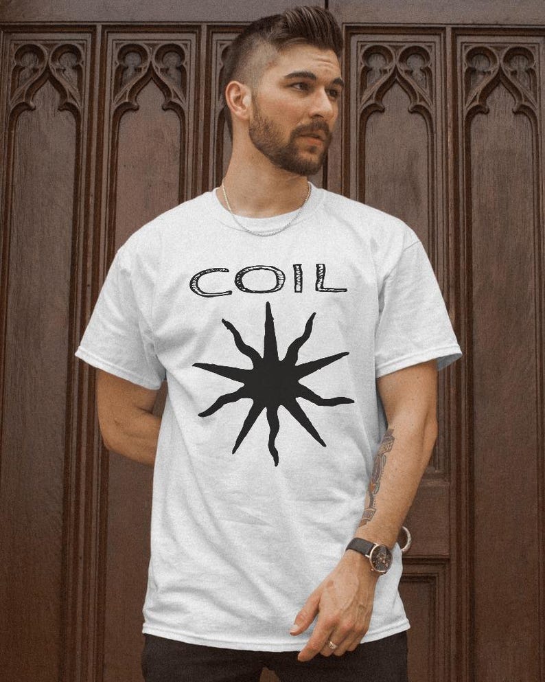 May include: White t-shirt with a black starburst design and the word "COIL" printed in black.
