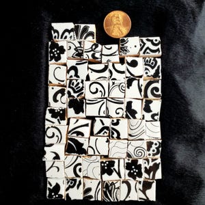May include: Black and white mosaic tiles with a floral pattern. The tiles are arranged in a random pattern and are approximately 1 inch square.
