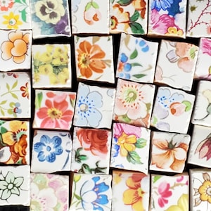 May include: A collection of small, square ceramic tiles with various floral patterns. The tiles are white with colorful flowers and leaves.
