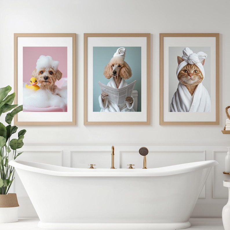 Puede incluir: Tres impresiones enmarcadas de animales con batas de ba&ntilde;o. Las impresiones est&aacute;n colgadas en una pared blanca sobre una ba&ntilde;era blanca. Los animales son un perro, un caniche y un gato.