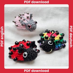 Puede incluir: Tres juguetes amigurumi de mariquita hechos a crochet. Uno es rosa con cuentas plateadas, otro es rojo con cuentas negras y el último es arcoíris con cuentas negras. Descarga PDF disponible.