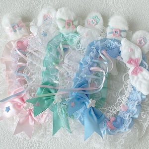 Pode incluir: Uma coleção de tiaras decorativas em tons pastel. Cada tiara apresenta um detalhe branco fofo, acabamento em renda e fitas em tons de rosa, azul e verde menta. Os enfeites incluem laços, corações e notas musicais.