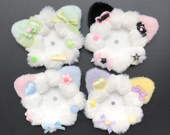 May include: Four fluffy, white, cloud-shaped hair clips with pastel accents. Each clip has a different coloured ear, decorated with bows, stars, hearts, and other embellishments. The clips have a cute, kawaii design, perfect for adding a touch of whimsy.