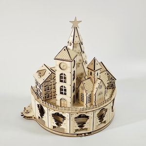 May include: A wooden Christmas village model with a clock tower, houses, and a Christmas tree topped with a star. The model is made of light-colored wood and features intricate cut-out details, creating a festive and decorative item.
