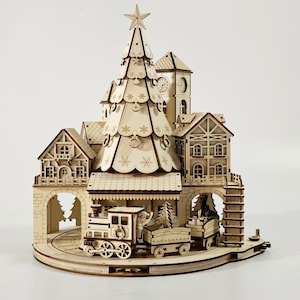 May include: A wooden Christmas village scene with a train, buildings, and a large Christmas tree. The tree is topped with a star. The train has a locomotive and two cars. The buildings include a clock tower and houses.